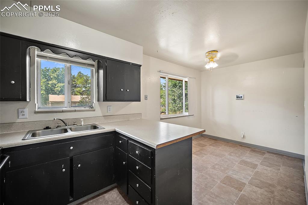 Image 14 of 19: Kitchen with dark cabinetry, a peninsula, and light countertops