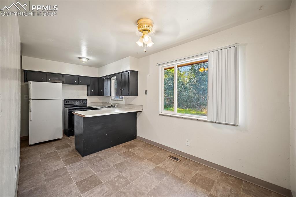 Image 15 of 19: Kitchen with freestanding refrigerator, a peninsula, light countertops, bla