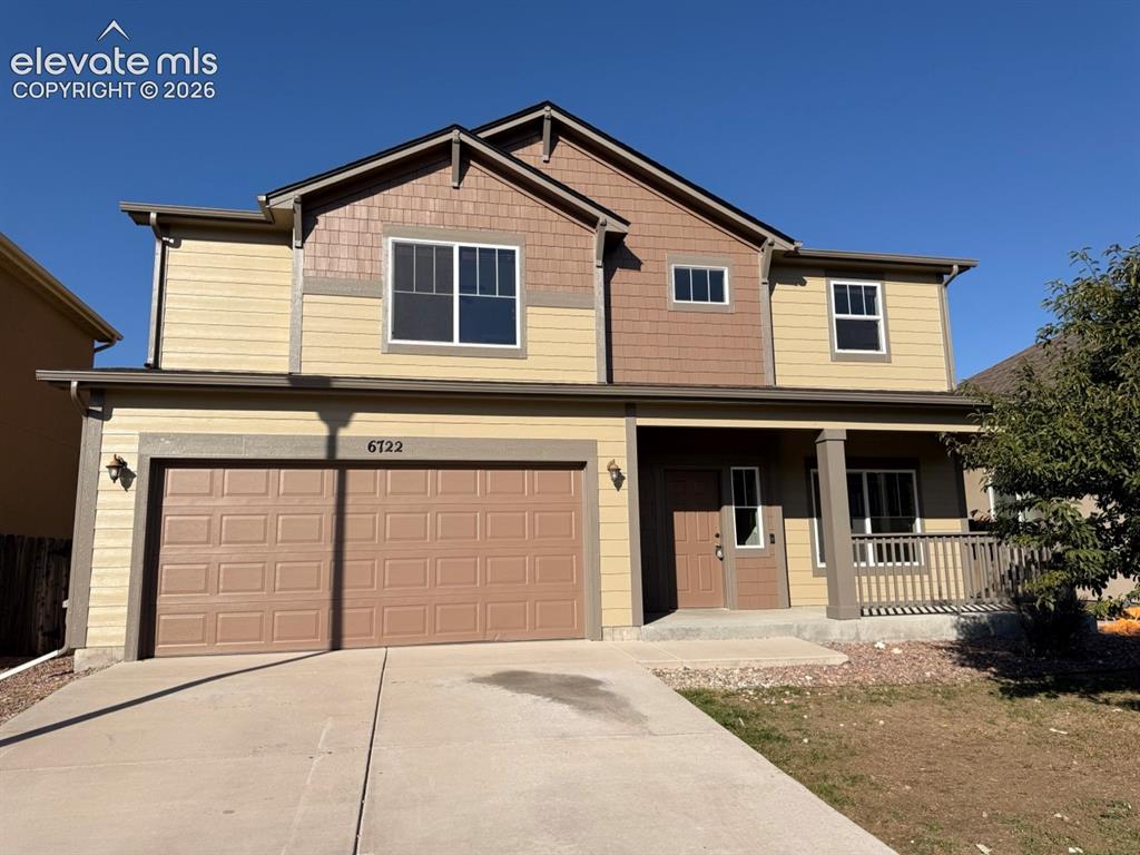 Caption: Two-story residence featuring a two-car garage, covered entry porch with railing, multiple windows, 
