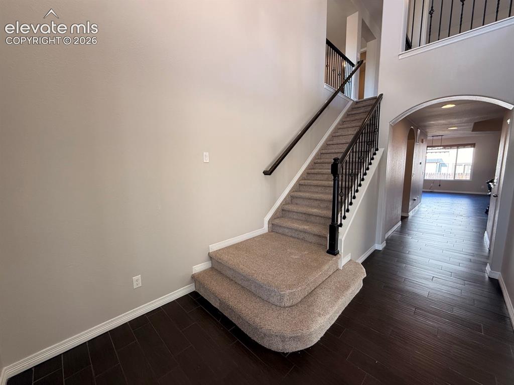 Image 3 of 50: Two-story foyer featuring dark wood-finish flooring, a carpeted staircase w