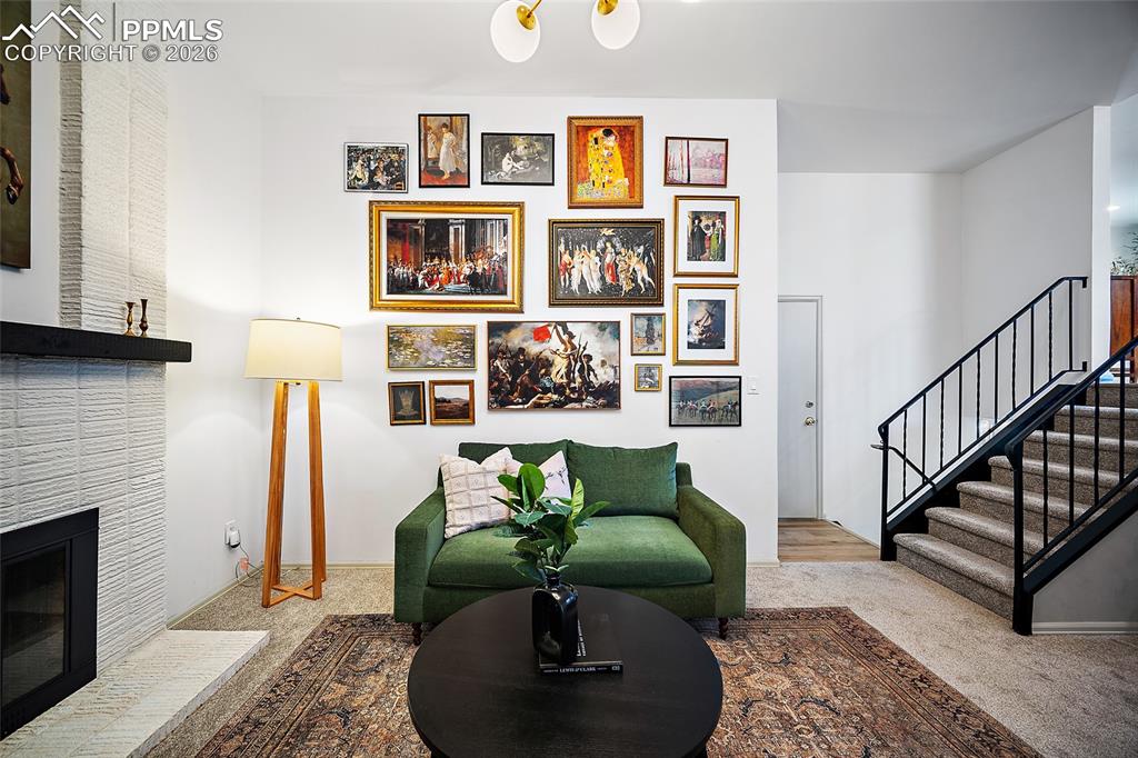 Image 17 of 45: Carpeted living room with a chandelier and a brick fireplace, door to the g