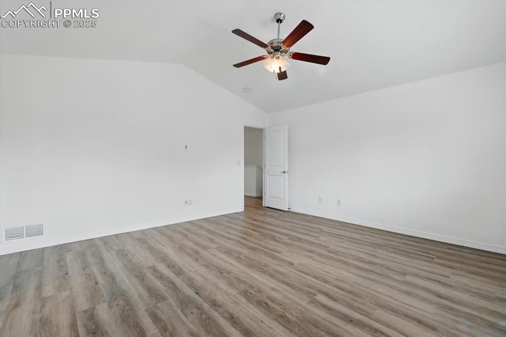Image 16 of 46: Spare room featuring a ceiling fan, vaulted ceiling, wood finished floors,