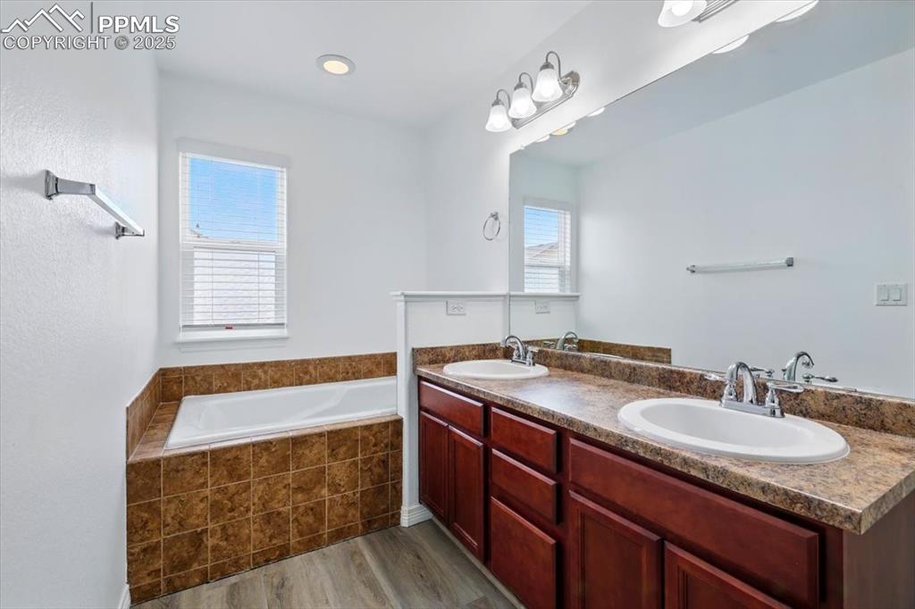 Image 17 of 46: Full bath with wood finished floors, a garden tub, and double vanity