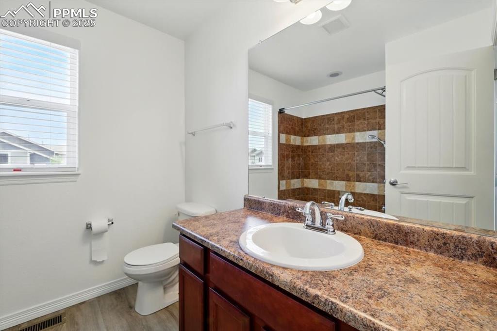 Image 27 of 46: Full bathroom with vanity, toilet, a shower, wood finished floors, and base
