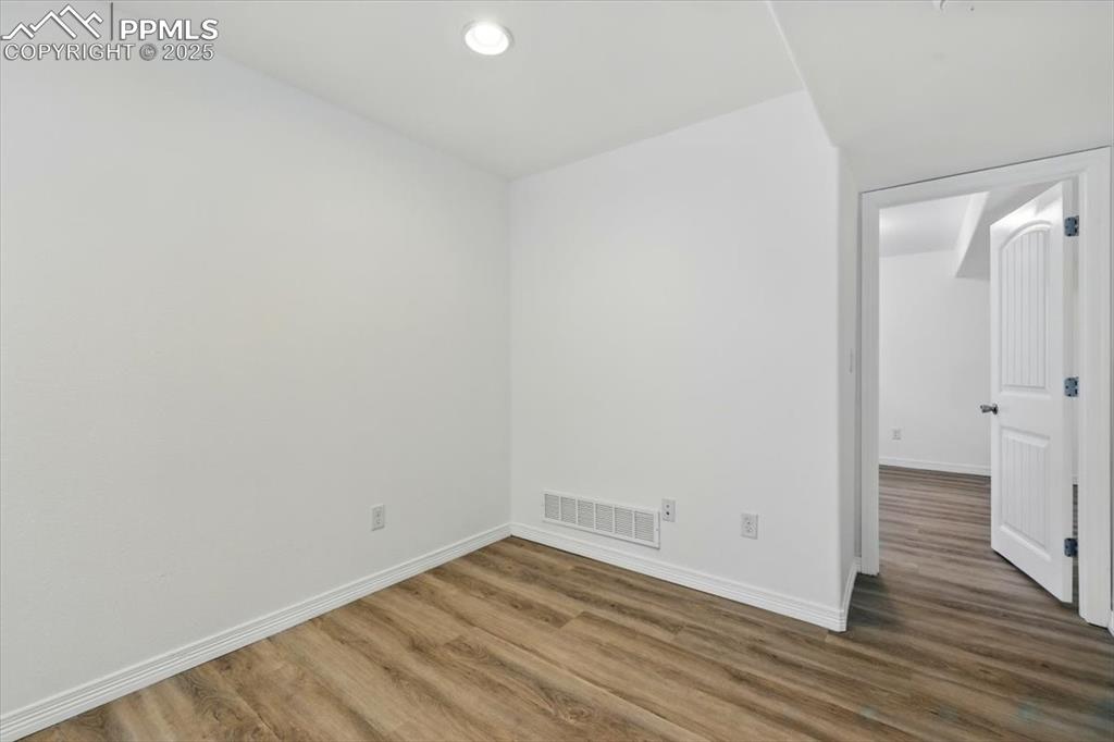 Image 30 of 46: Empty room featuring wood finished floors, baseboards, and recessed lightin
