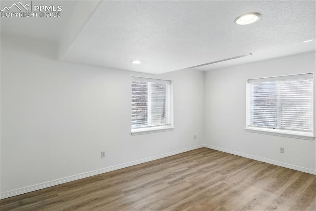 Image 38 of 46: Spare room with wood finished floors, a textured ceiling, baseboards, and r