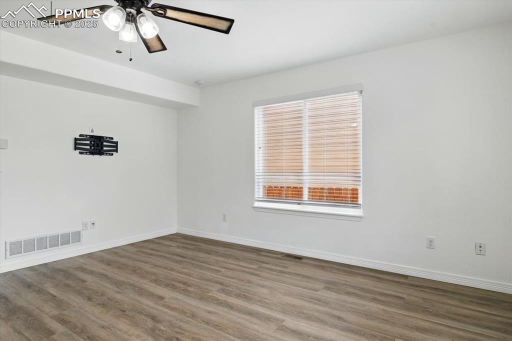 Image 8 of 46: Unfurnished room featuring wood finished floors, baseboards, and ceiling fa