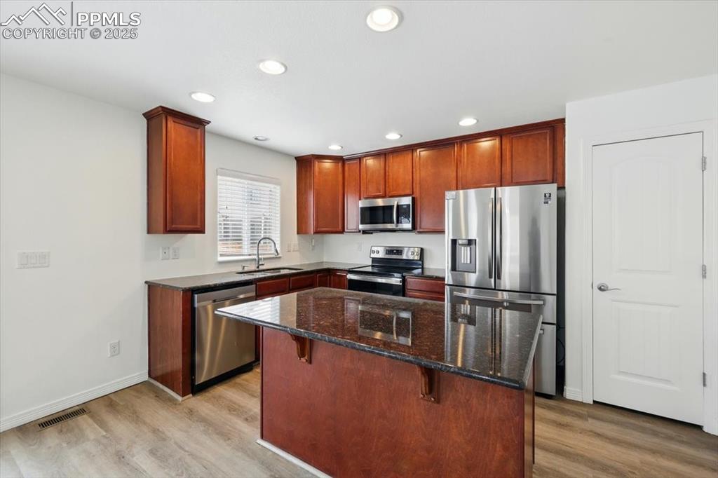 Image 9 of 46: Kitchen with appliances with stainless steel finishes, a sink, light wood f