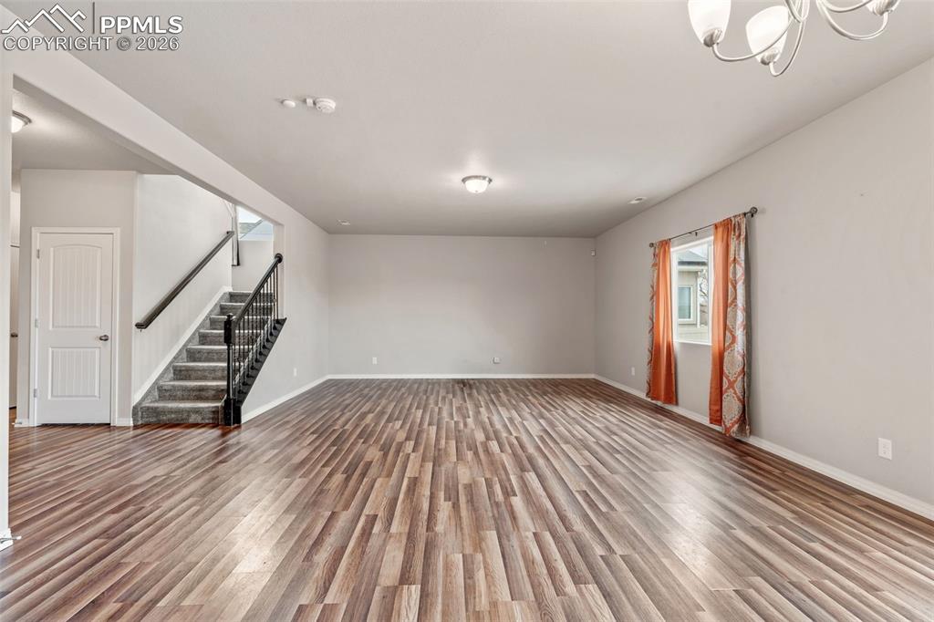 Image 13 of 50: Empty room featuring wood finished floors and suspended lighting