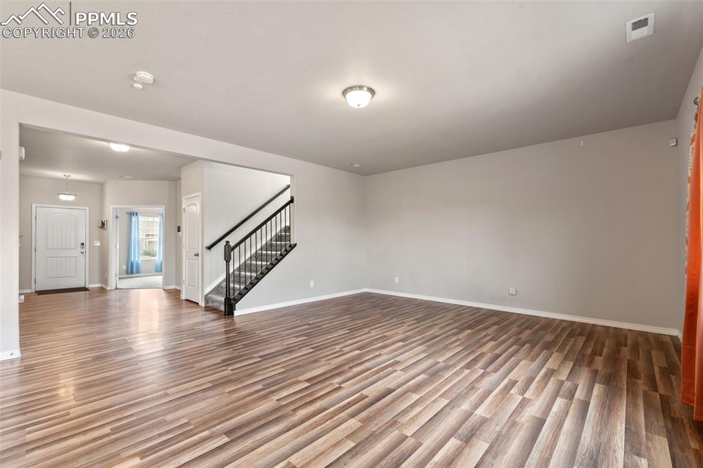 Image 14 of 50: Unfurnished living room with stairs and light wood-style flooring