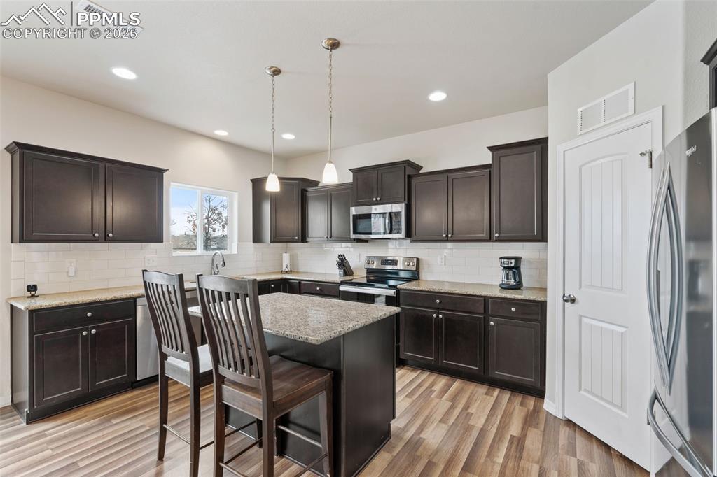 Image 21 of 50: Kitchen with a kitchen bar, dark wood finish cabinets, hanging light fixtur