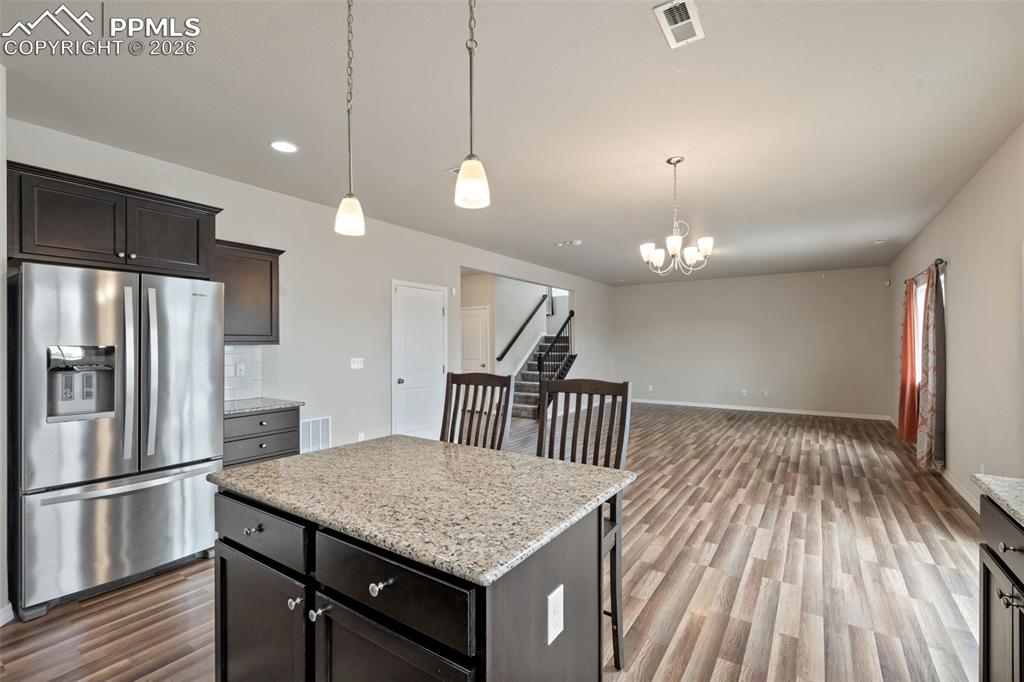 Image 22 of 50: Kitchen with stainless steel fridge with ice dispenser, light stone counter