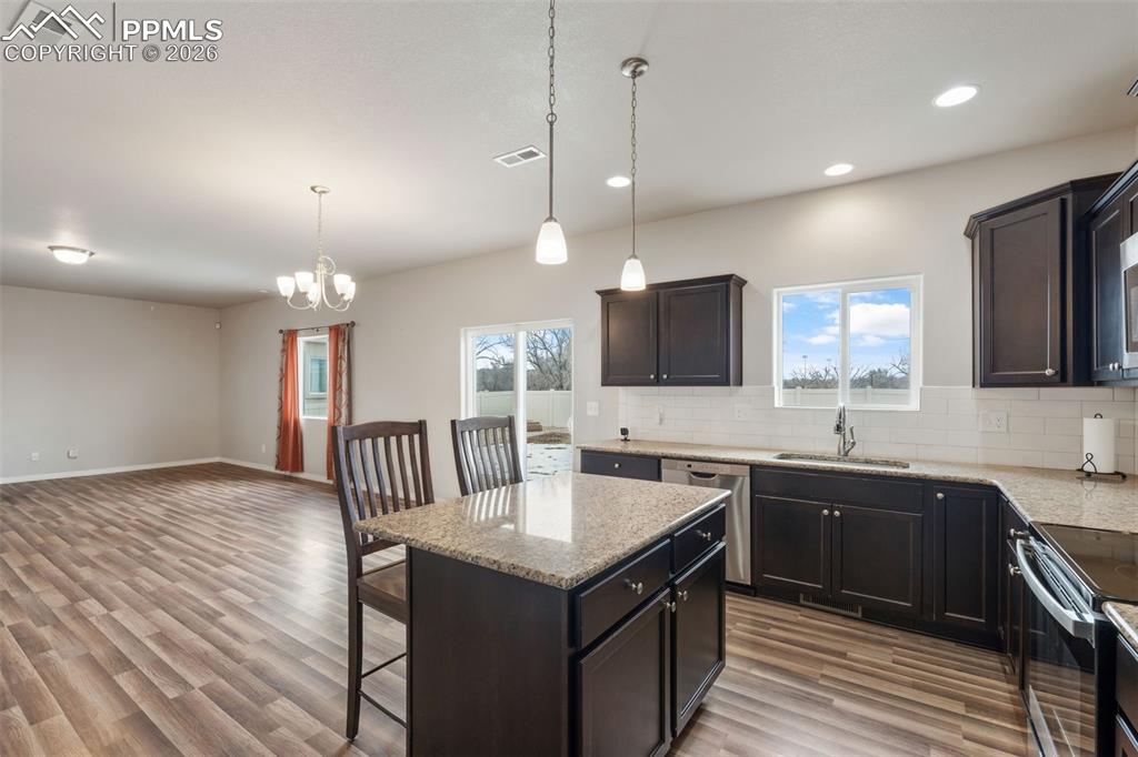 Image 23 of 50: Kitchen featuring a breakfast bar area, light stone counters, a kitchen isl
