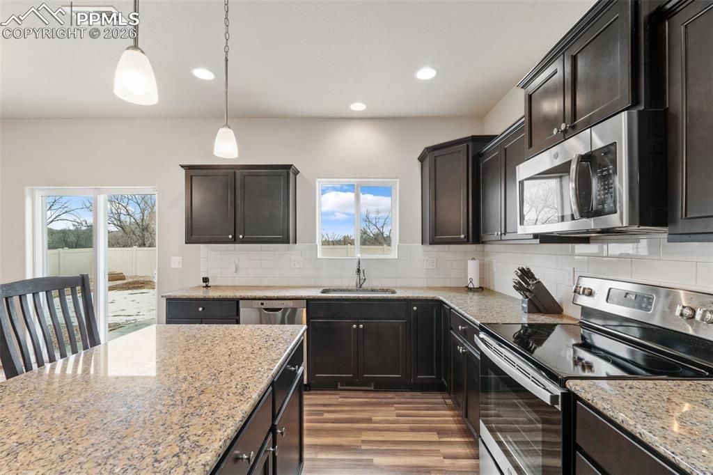 Image 24 of 50: Kitchen featuring stainless steel appliances, hanging light fixtures, light