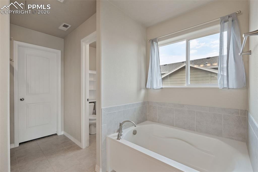 Image 37 of 50: Full bath featuring a garden tub and light tile patterned floors