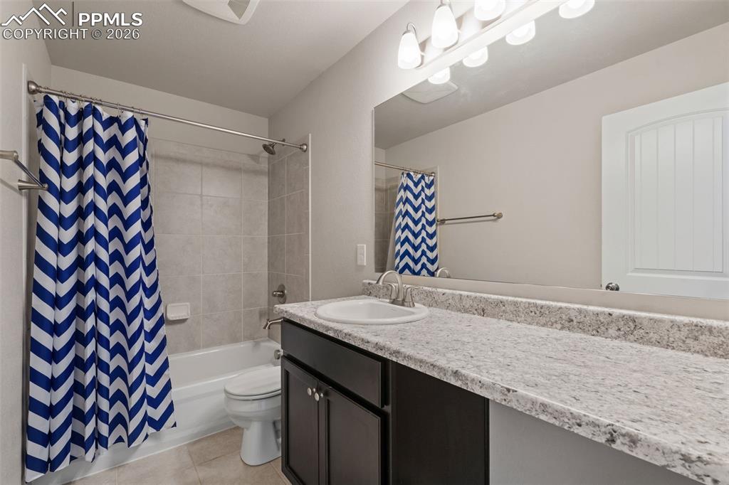 Image 42 of 50: Bathroom featuring vanity, shower / bath combo with shower curtain, and lig