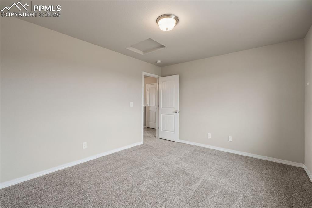 Image 44 of 50: Carpeted spare room featuring attic access and baseboards