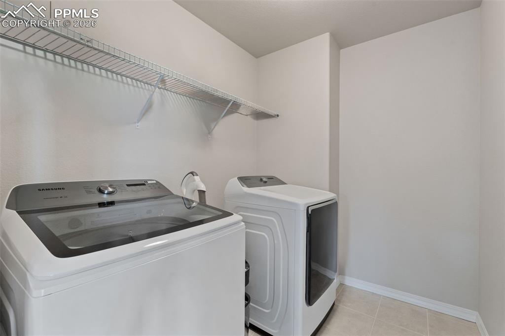 Image 45 of 50: Laundry area with washer and clothes dryer and light tile patterned floorin