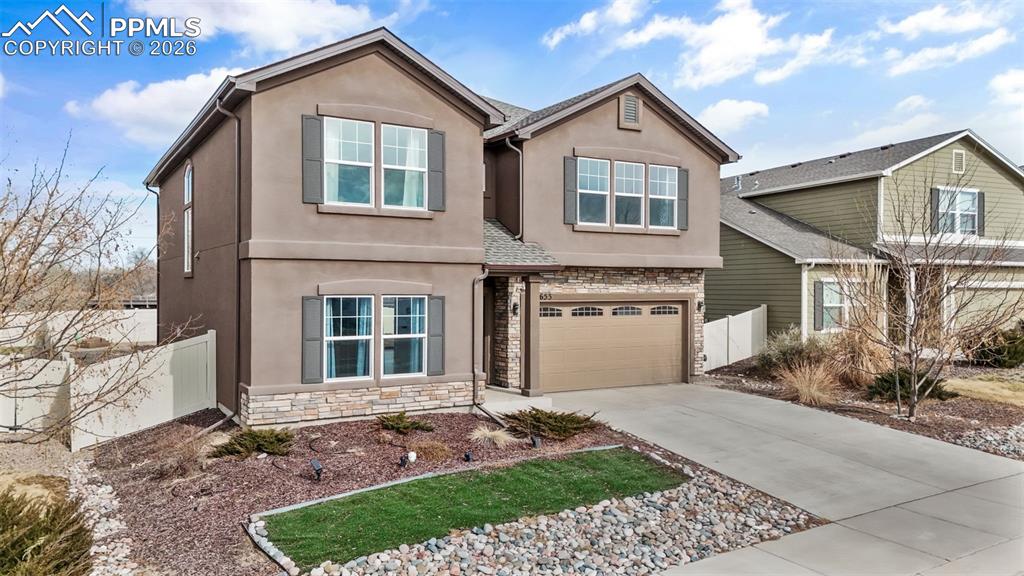 Image 5 of 50: View of front of home with stone siding, stucco siding, a garage, and concr
