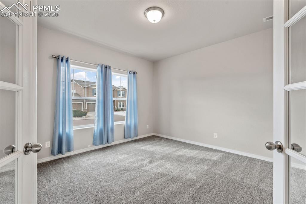 Image 9 of 50: Empty room featuring french doors and carpet floors