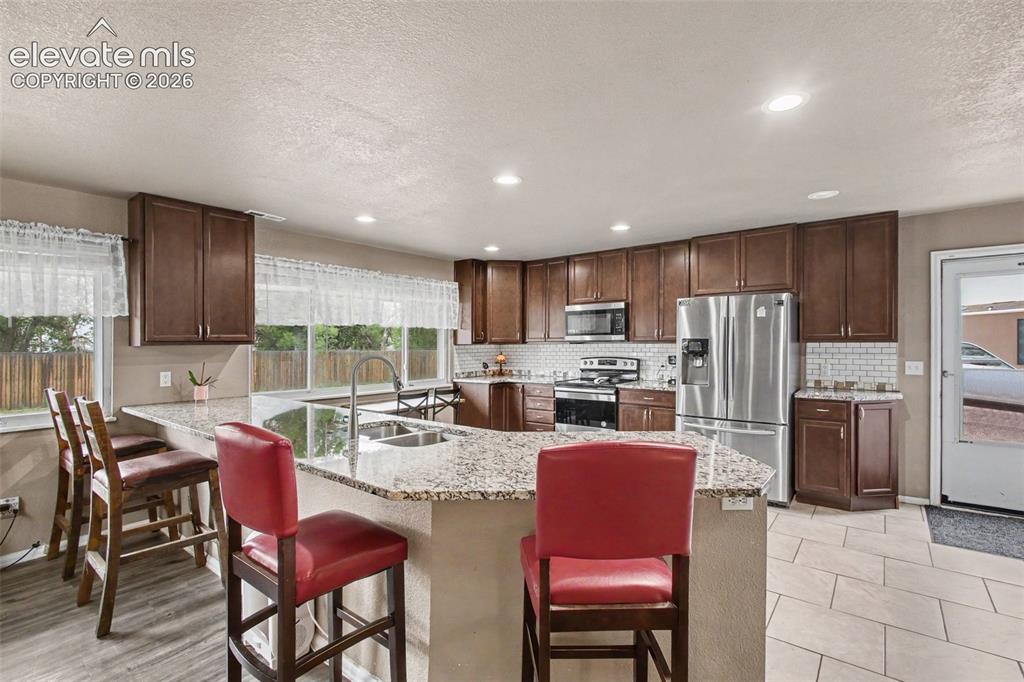 Image 11 of 45: Center granite countertop island with seating, perfect for casual meals, mo