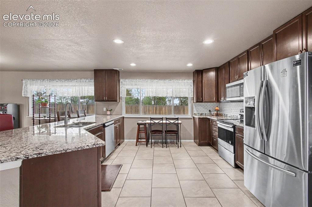 Image 12 of 45: Granite countertops, stylish backsplash, stainless steel appliances, and am