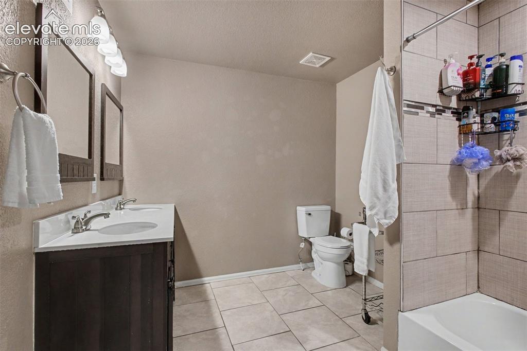 Image 22 of 45: 2nd full bath with dual sinks, tile flooring and tub/shower