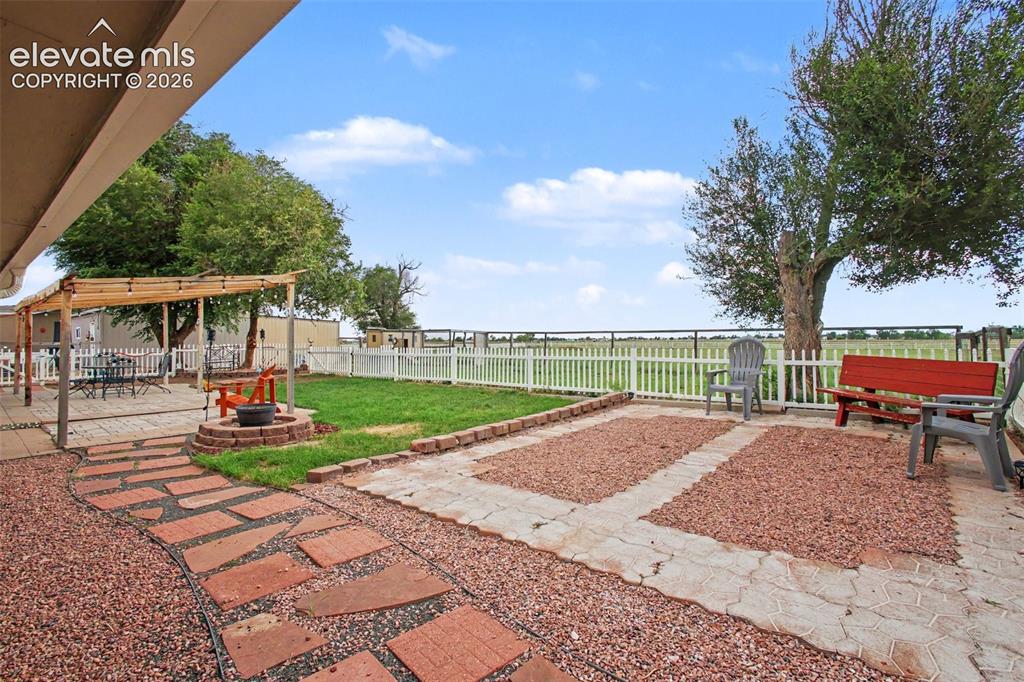 Image 24 of 45: Beautiful concrete paver patio featuring a fire pit, bench, and comfortable