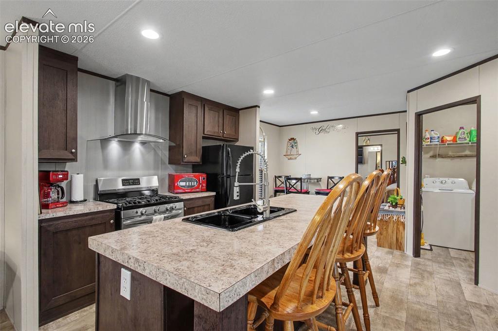 Image 31 of 45: 2nd Home: Modern kitchen featuring LVT flooring, a stylish vent hood, gas