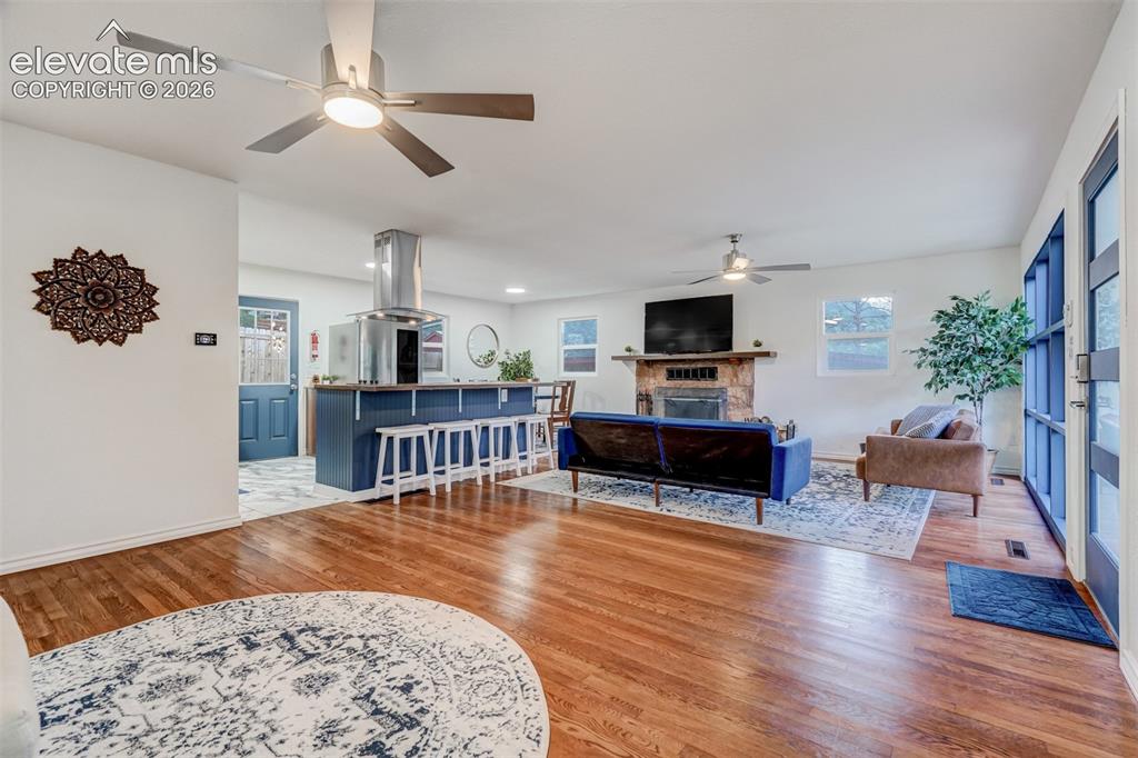 Image 13 of 41: Wood-finish flooring throughout the main area, stone fireplace, kitchen isl