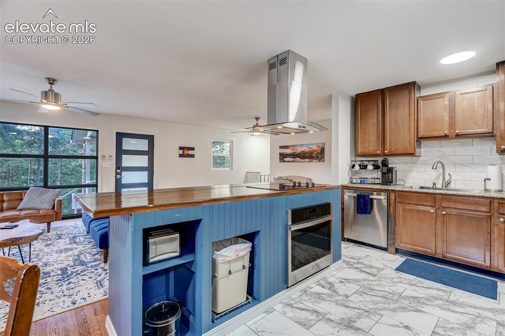 Image 20 of 41: Kitchen featuring a wood-finish island with a blue base, stainless steel ap