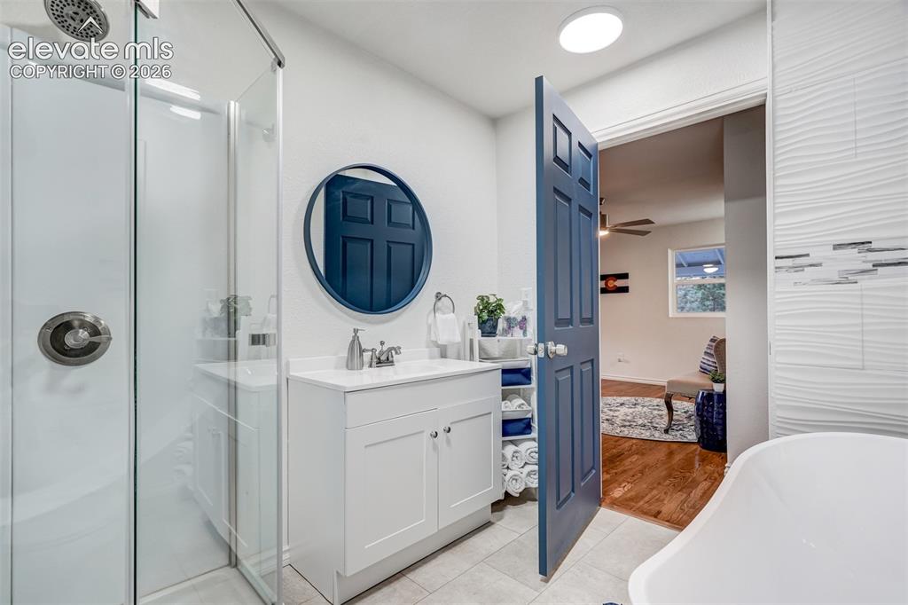 Image 22 of 41: Walk-in shower with glass enclosure, single vanity with white cabinetry, ro