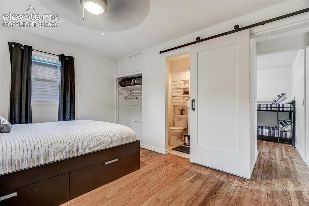 Image 29 of 41: Wood-finish flooring, built-in storage, modern ceiling fan, white barn door