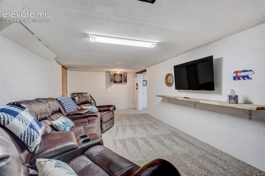 Image 33 of 41: Carpeted flooring, wall-mounted television, and built-in shelving