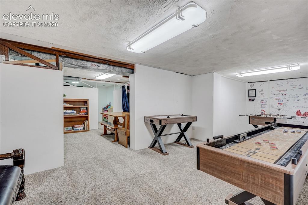 Image 35 of 41: Carpeted recreation room with exposed ceiling beams and recessed lighting