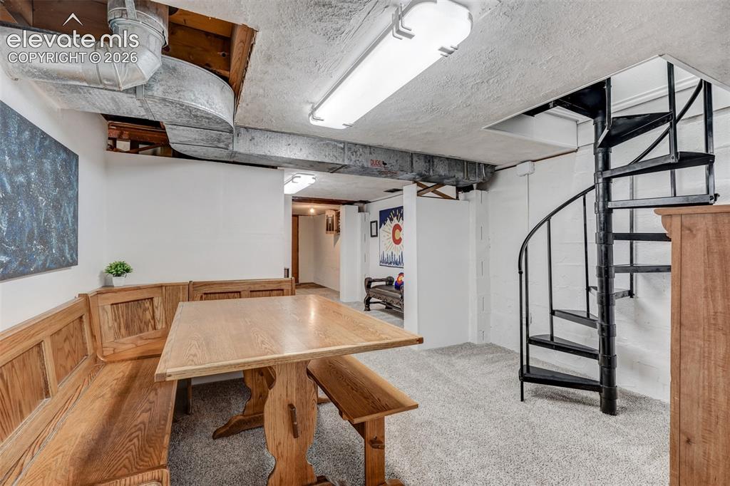 Image 38 of 41: Carpeted interior space featuring a black spiral staircase, exposed ceiling