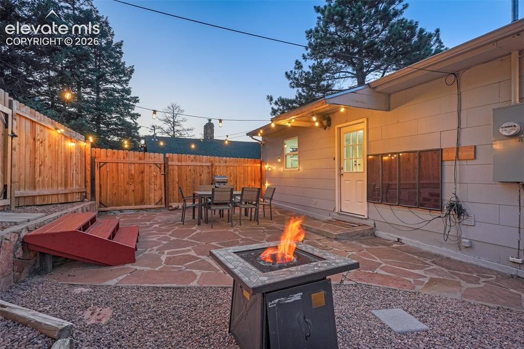 Image 4 of 41: Flagstone patio with a natural wood fence and exterior lighting