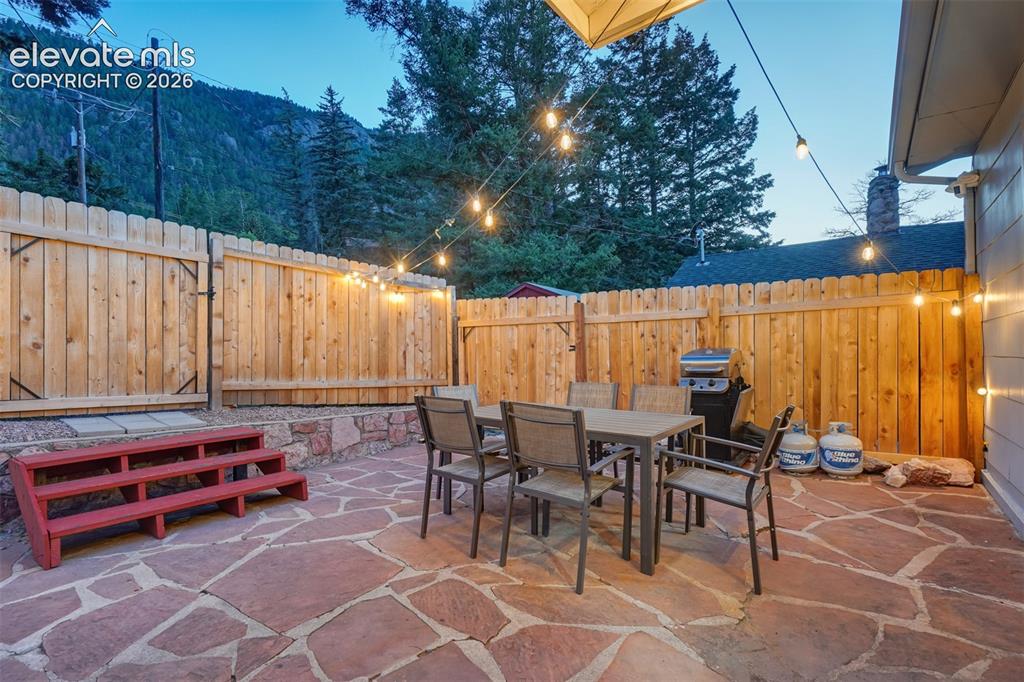 Image 7 of 41: Expansive flagstone patio with a privacy fence, stone retaining wall, and s
