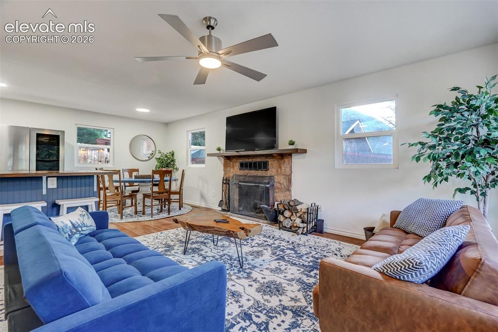 Image 9 of 41: Stone-clad fireplace with a wood mantle, wood-finish flooring, and a modern