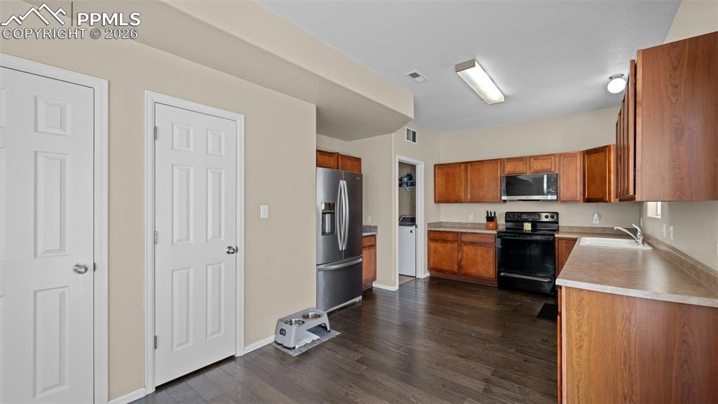 Image 30 of 37: Kitchen featuring black appliances, light countertops, wood finish cabinets