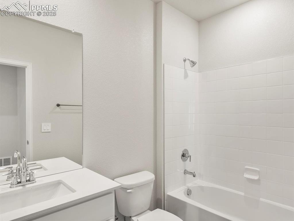 Image 13 of 28: Full bath with a textured wall, shower / bath combination, and vanity