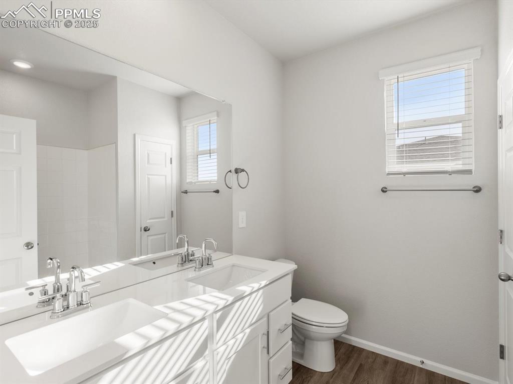 Image 19 of 28: Full bath with dark wood finished floors, healthy amount of natural light, 