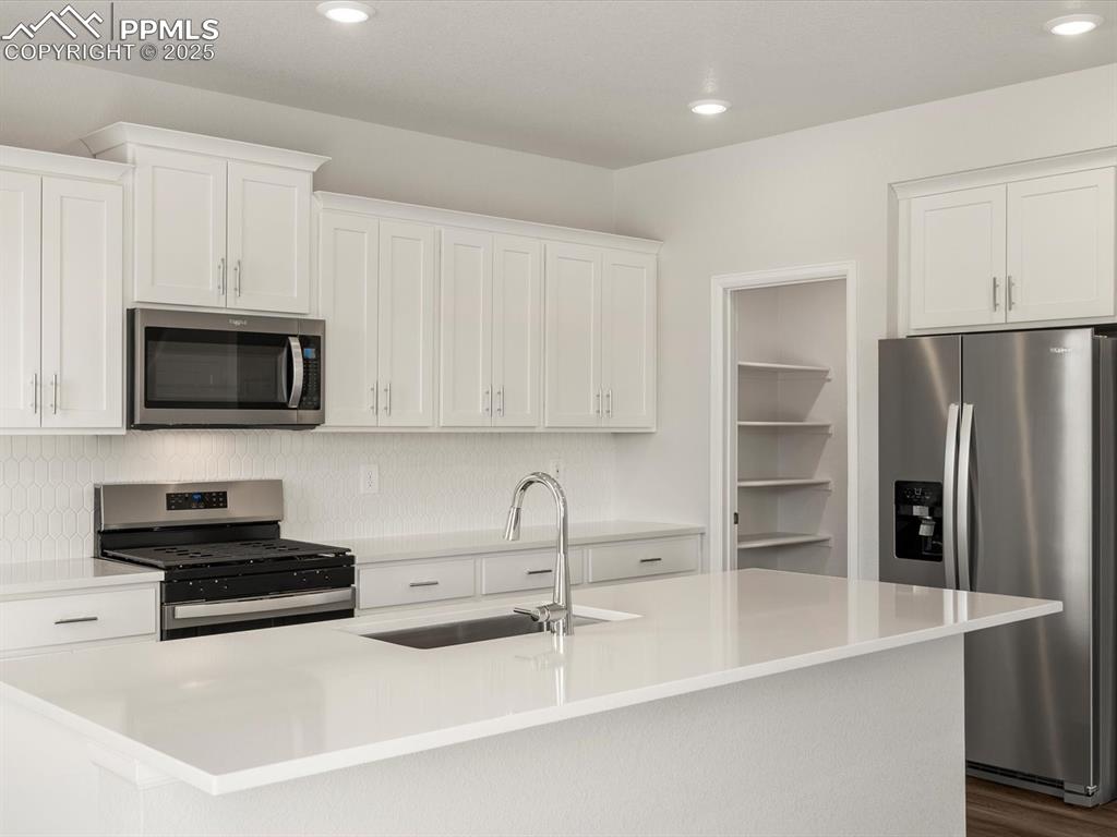 Image 4 of 28: Kitchen featuring stainless steel appliances, white cabinetry, recessed lig