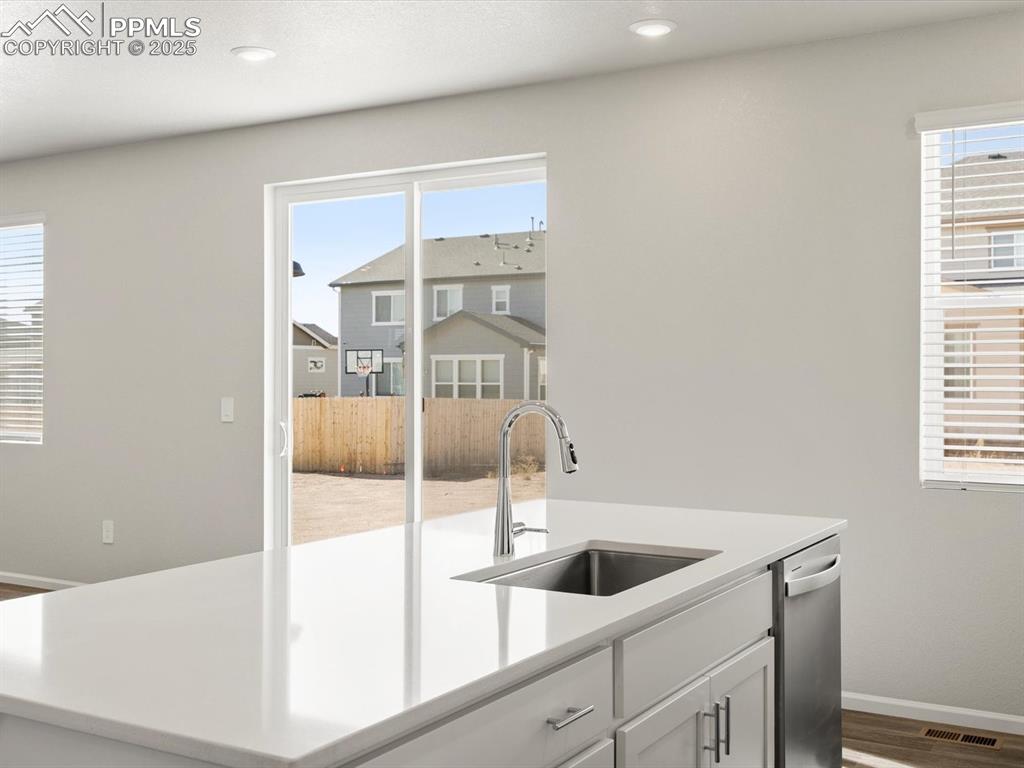 Image 6 of 28: Kitchen with an island with sink, white cabinetry, plenty of natural light,