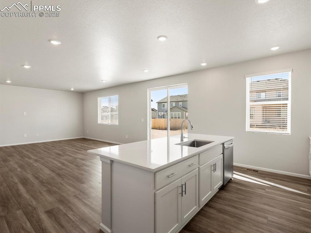 Image 7 of 28: Kitchen with white cabinetry, a center island with sink, dark wood finished