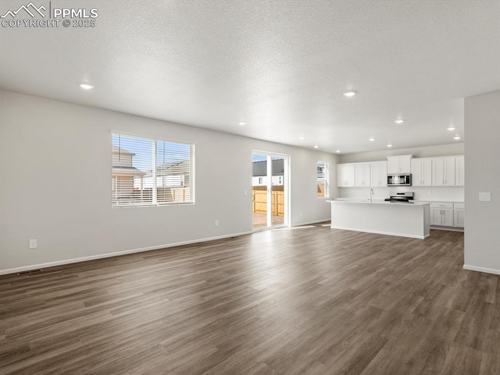 Image 8 of 28: Unfurnished living room with dark wood-style floors, recessed lighting, and