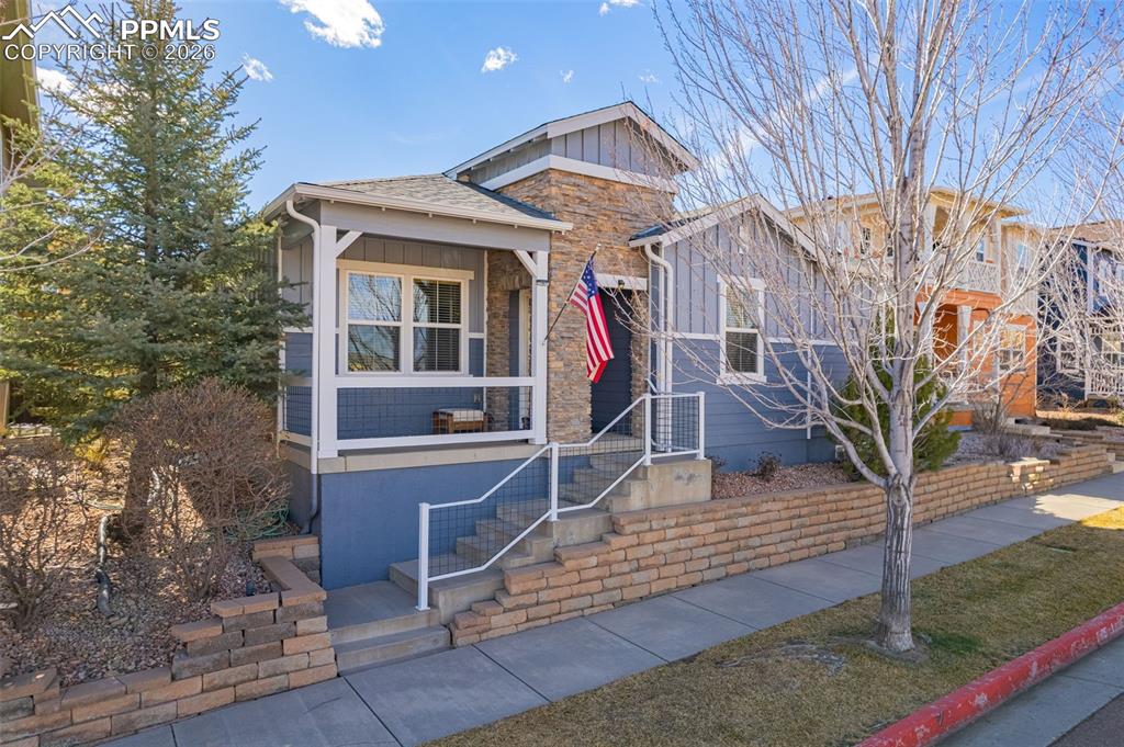 Image 1 of 42: View of front of house with stone siding, board and batten siding, and a po