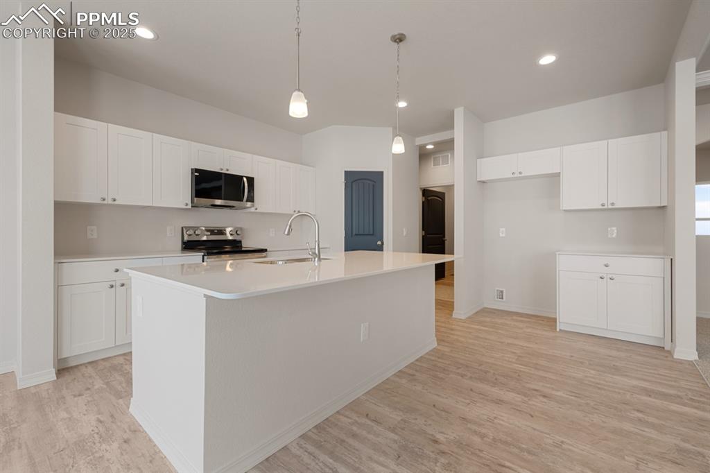 Image 12 of 22: Kitchen featuring light wood-type flooring, white cabinetry, appliances wit