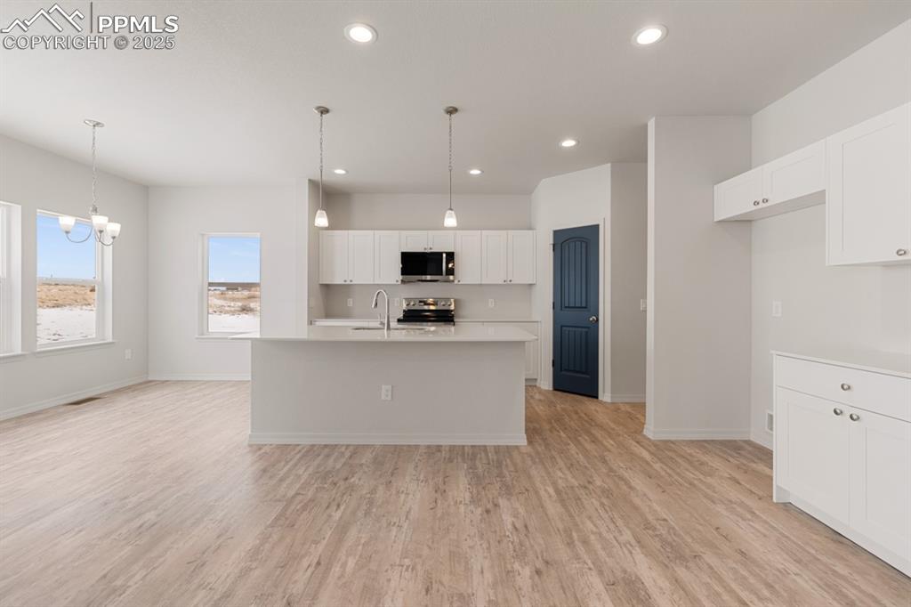 Image 13 of 22: Kitchen featuring light countertops, an island with sink, white cabinetry, 