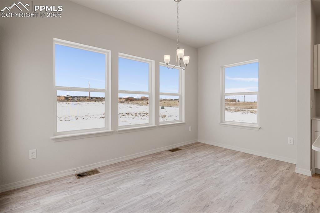Image 16 of 22: Empty room with a chandelier and light wood-style flooring